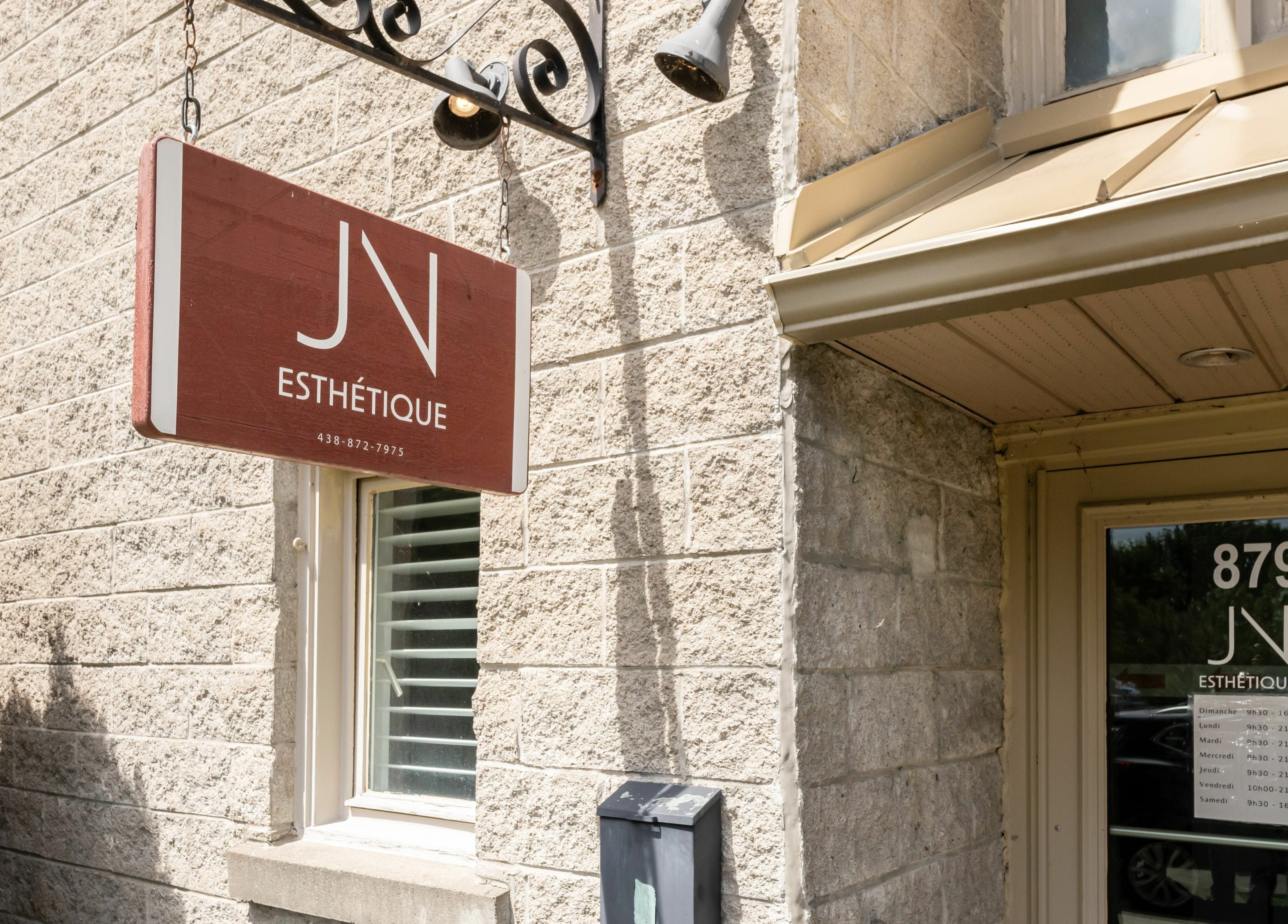 Entrée de JN Esthétique à Terrebonne, Québec, CA. Panneau et porte affichant l'adresse 879.