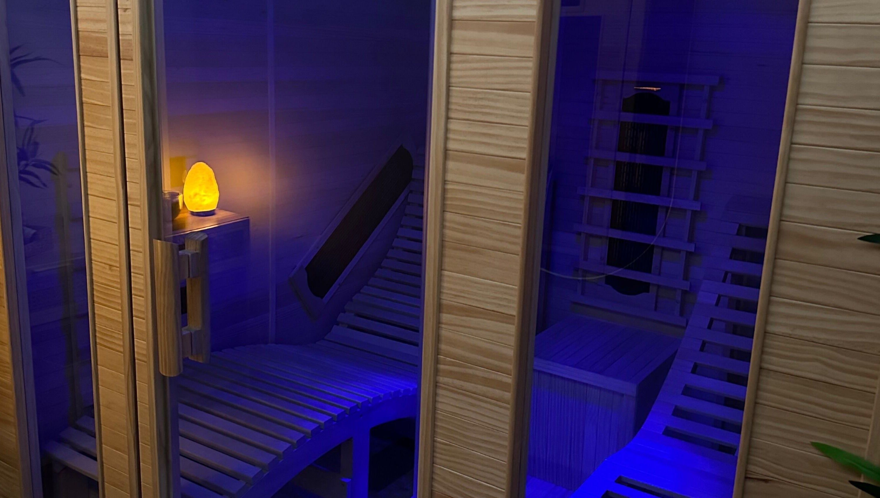 Elegant infrared sauna at Glow Szn, Condell Park, New South Wales, AU with glowing salt lamp and wooden benches.