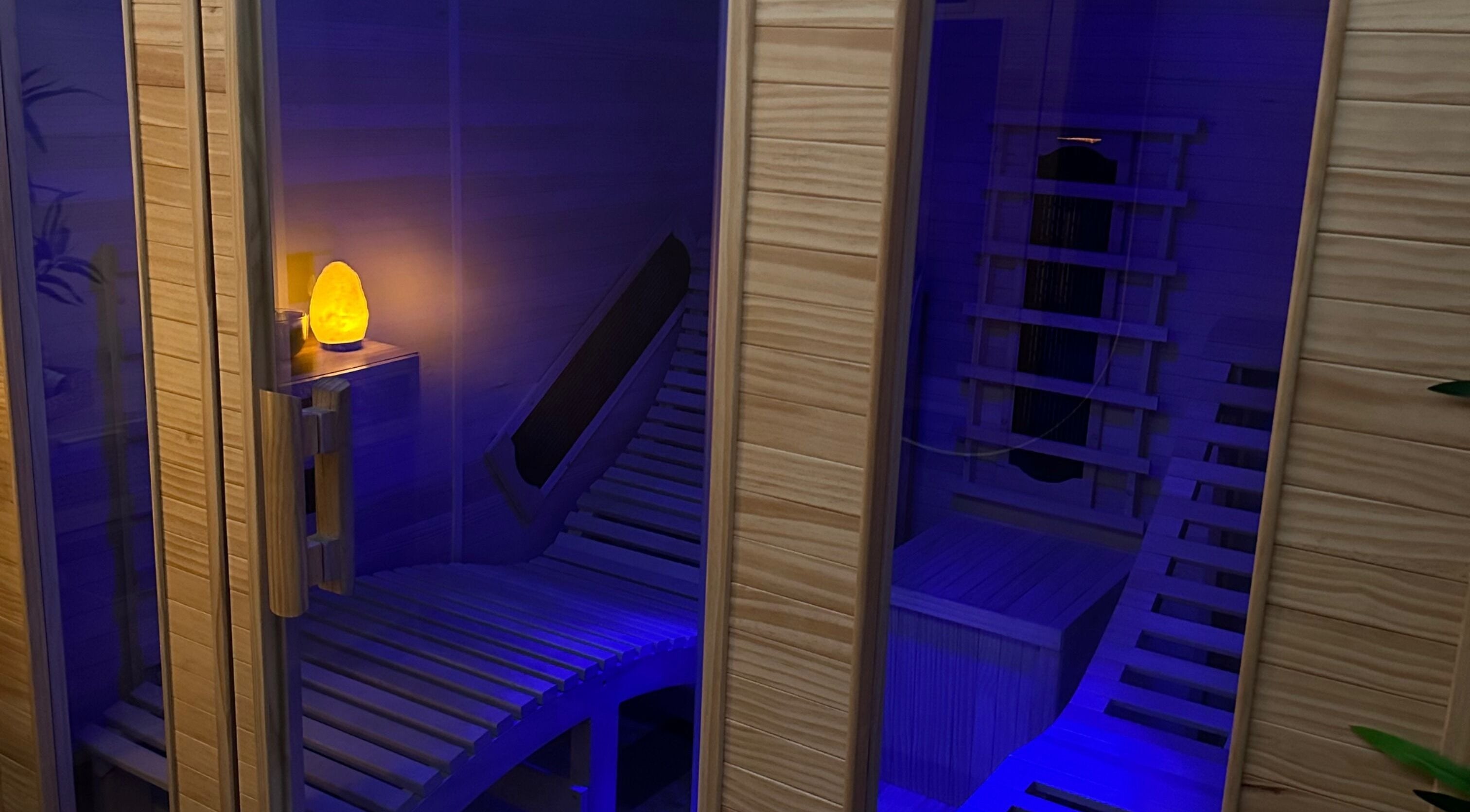 Elegant infrared sauna at Glow Szn, Condell Park, New South Wales, AU with glowing salt lamp and wooden benches.