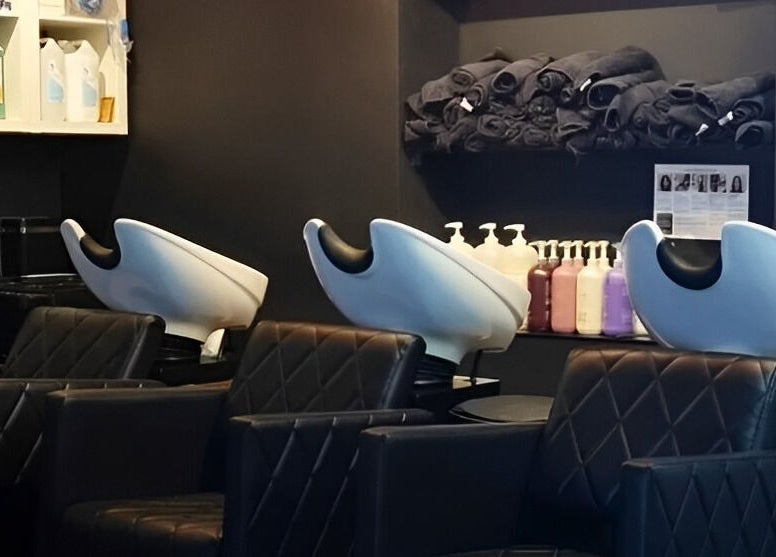 Elegant salon wash station at E.L.M Academy in Bacup, England, GB, with modern black seating and amenities.