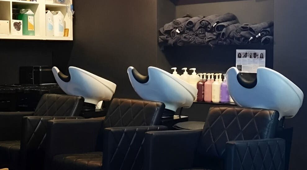 Elegant salon wash station at E.L.M Academy in Bacup, England, GB, with modern black seating and amenities.