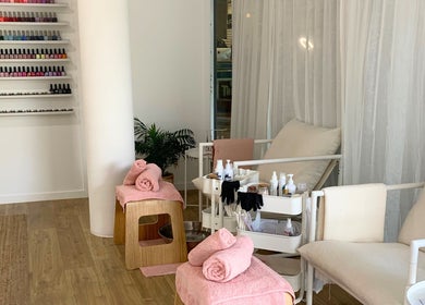 Relaxing nail care area at Palm Beauty Noosa, Noosaville, Queensland, AU, with cozy chairs and vibrant polish display.