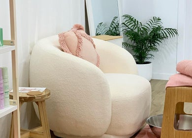 Chic relaxation space at Palm Beauty Noosa, Noosaville, Queensland, AU, with plush chair and calming decor.