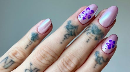 Hand with pink and purple floral nails at Kayley Diane Nails, Colchester, England, GB.