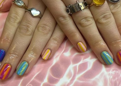 Vibrant, striped nails from Kayley Diane Nails in Colchester, England, GB on a soft pink background.