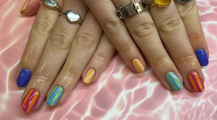 Vibrant, striped nails from Kayley Diane Nails in Colchester, England, GB on a soft pink background.