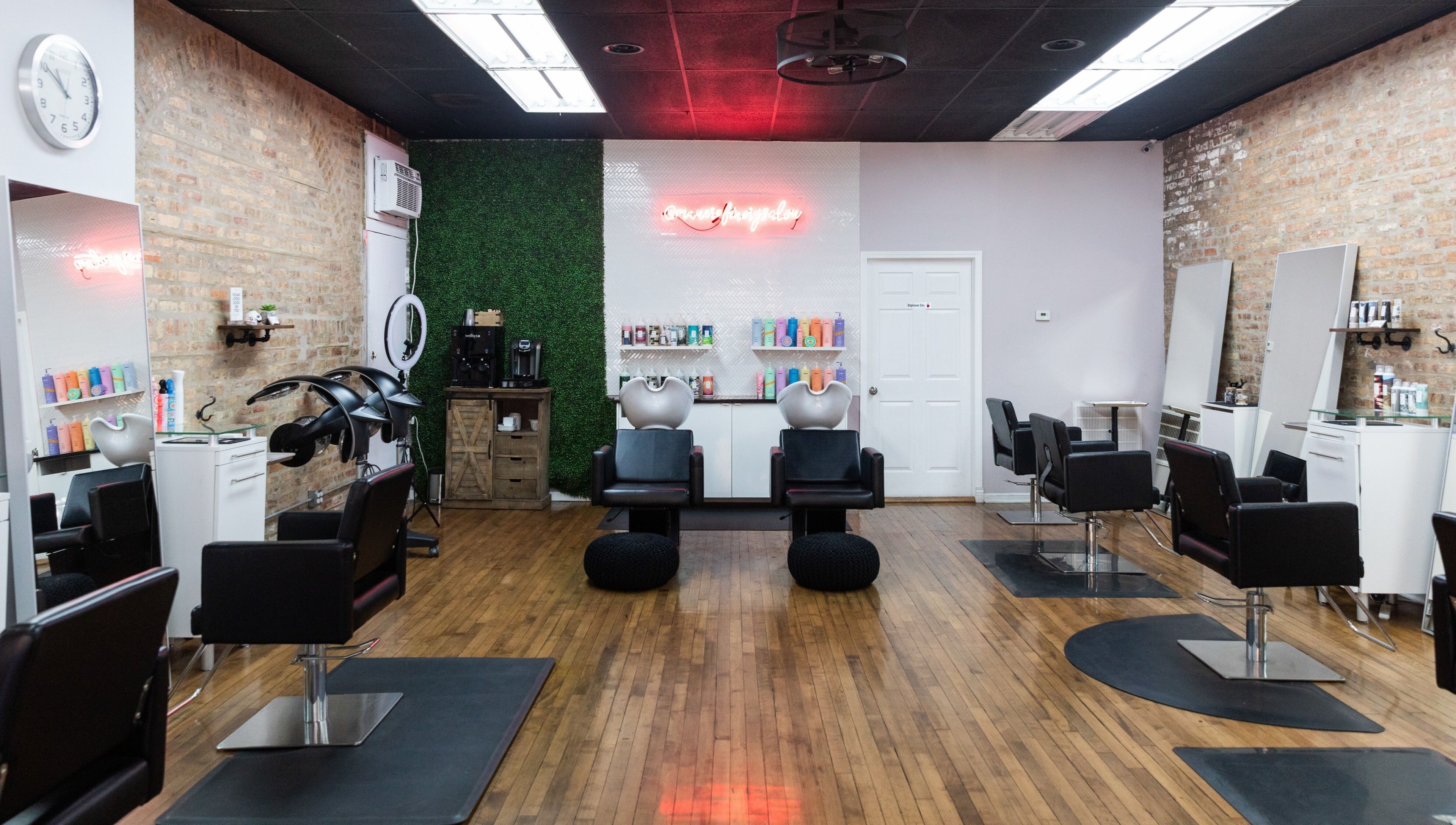 Modern styling stations at Mane Refinery Salon, Chicago, IL, US, with sleek black chairs and vibrant products.