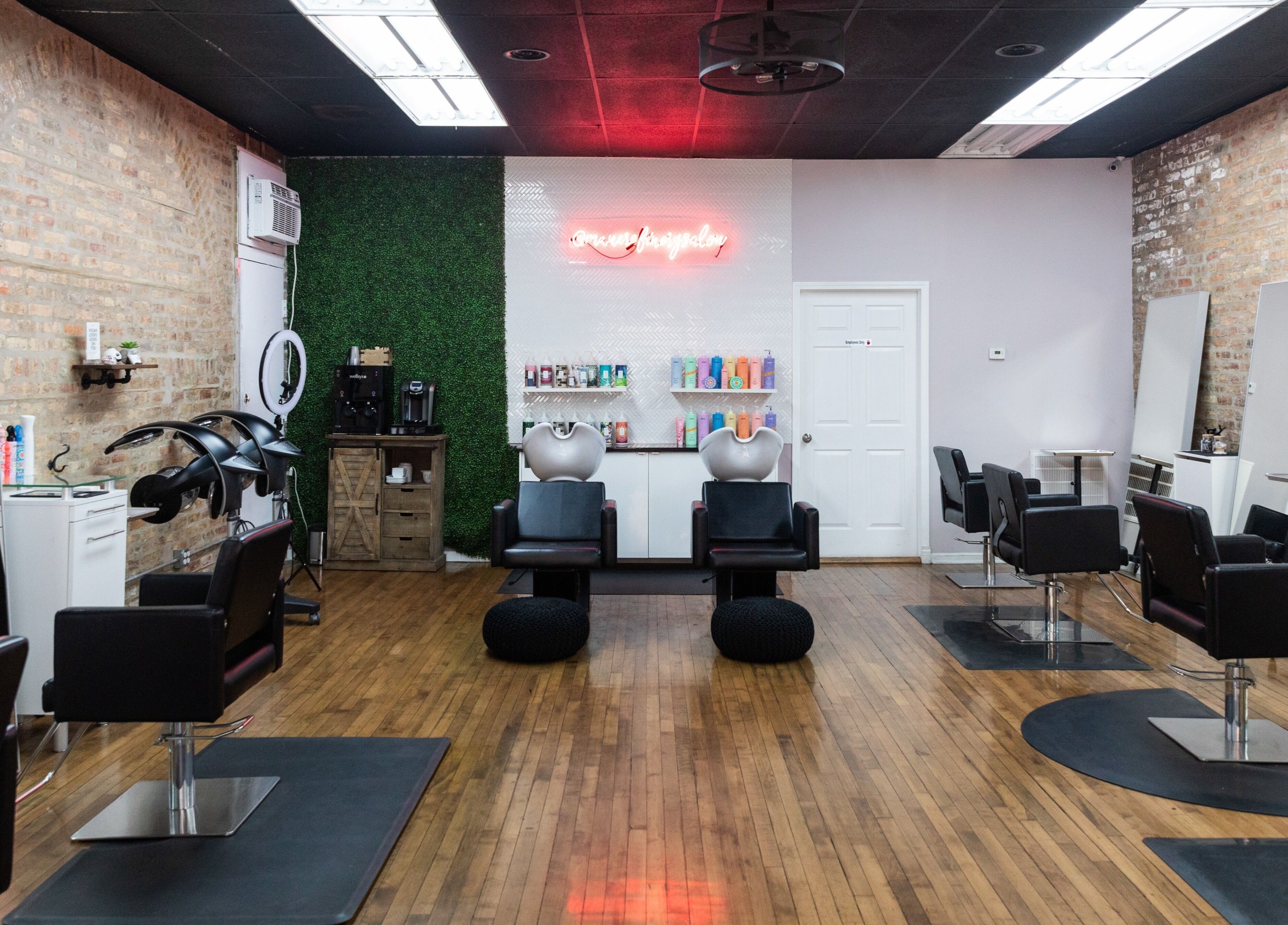 Modern styling stations at Mane Refinery Salon, Chicago, IL, US, with sleek black chairs and vibrant products.