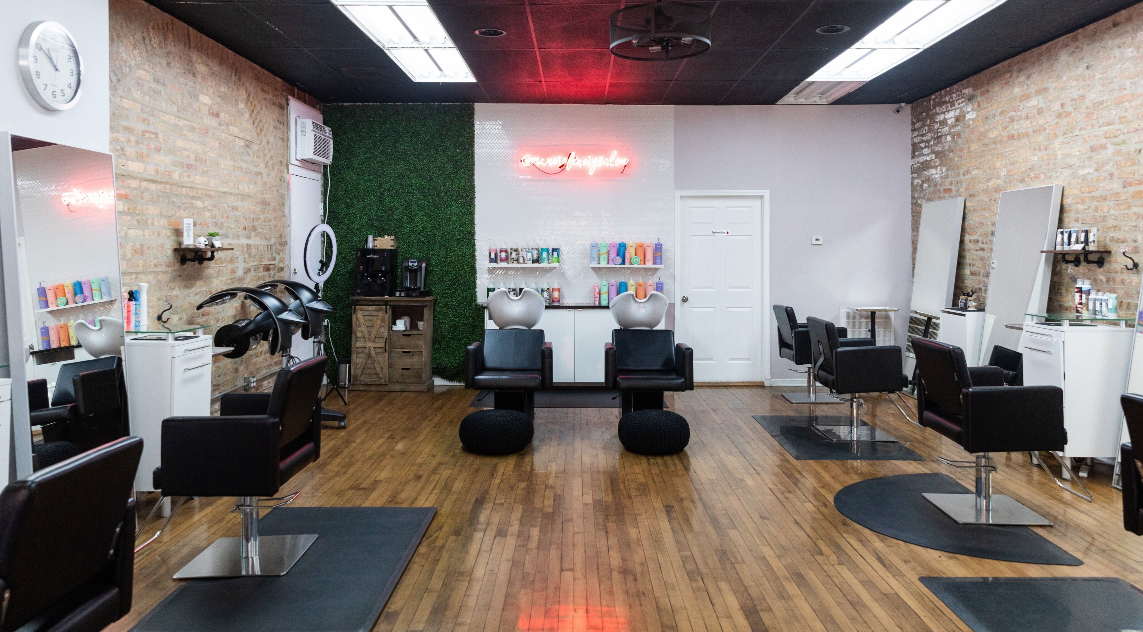 Modern styling stations at Mane Refinery Salon, Chicago, IL, US, with sleek black chairs and vibrant products.