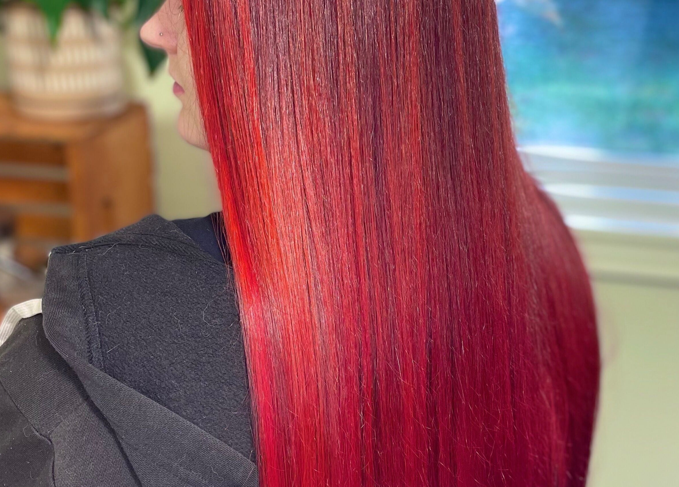 Vibrant red hair styled at Modcrown Creations, Oshawa, Ontario, CA showcasing sleek and glossy finish.