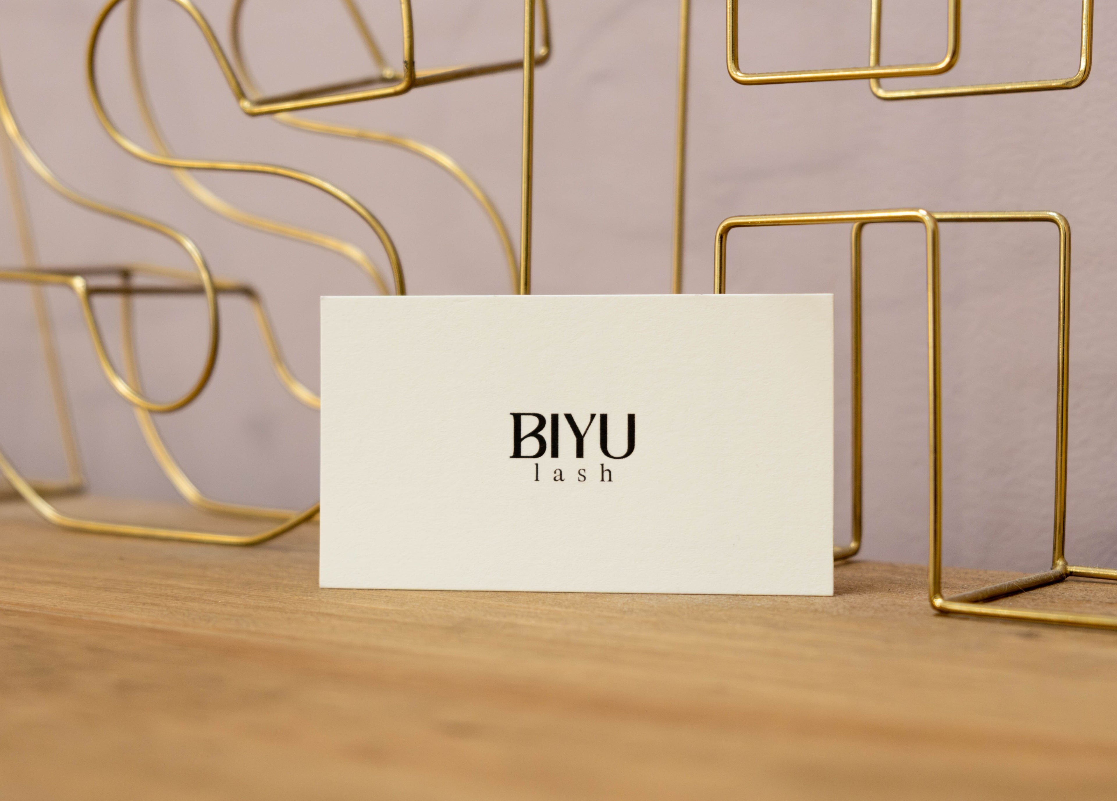 BIYU Lash Hanover Sq. card on wooden table, London, England, GB with gold wire decor.