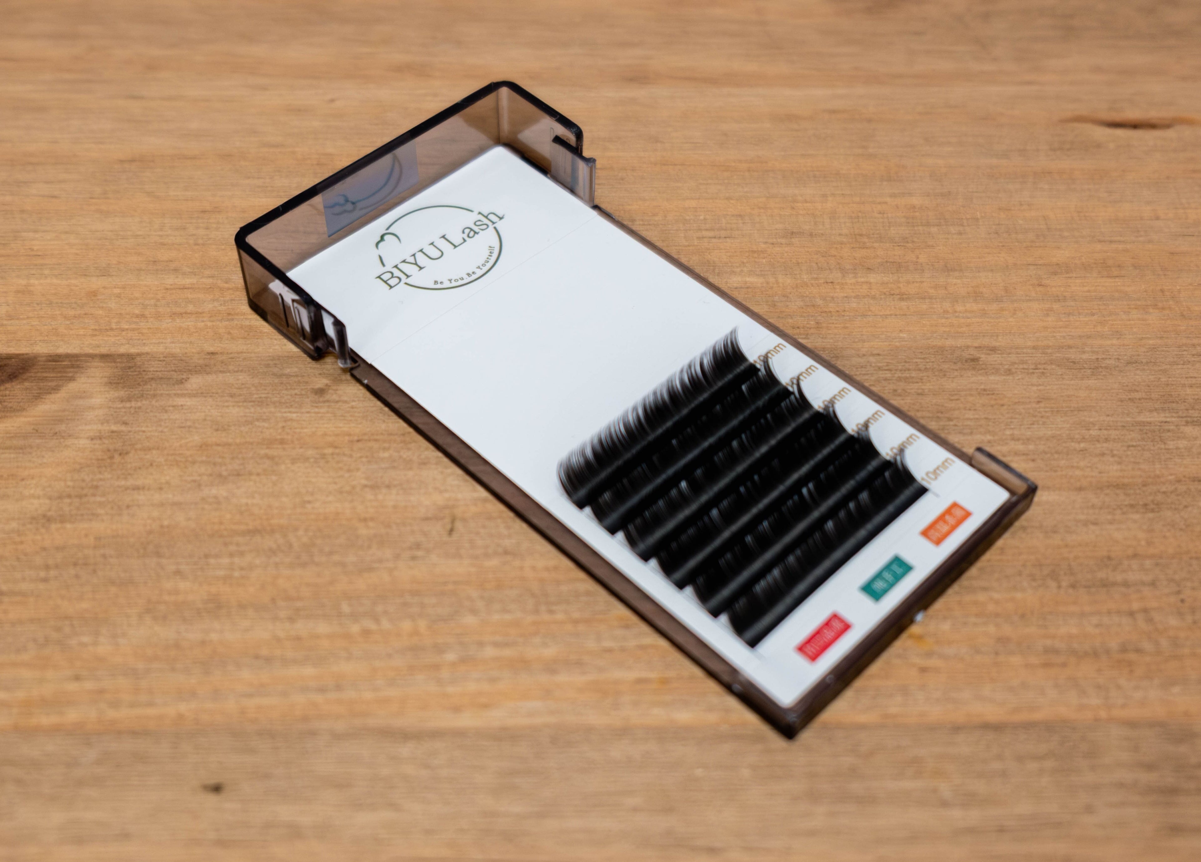 Close-up of BIYU Lash Hanover Sq. lash extensions in London, England, GB displayed on a wooden table.