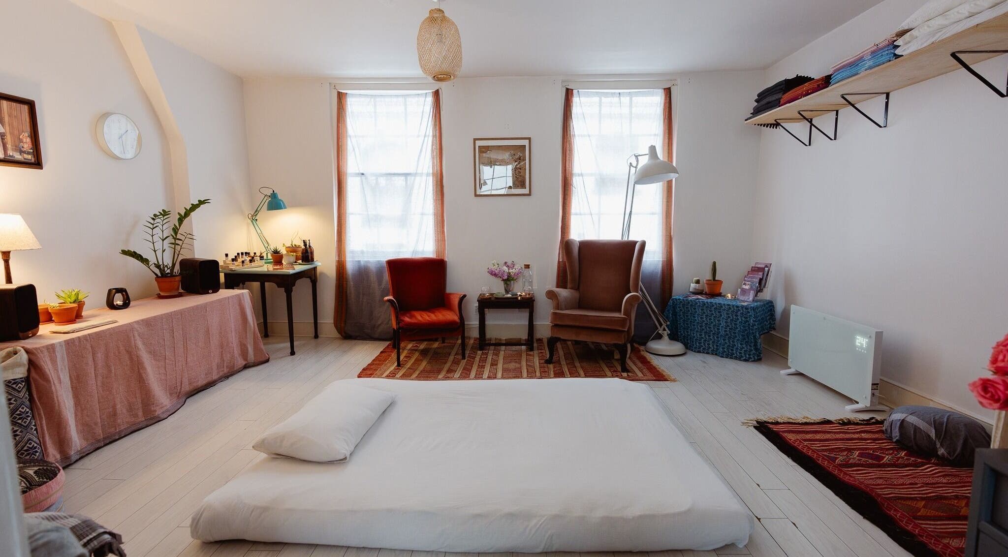 A serene massage room at Ayurvedic Yoga Massage London, London, England, GB with cozy seating and a massage mat.