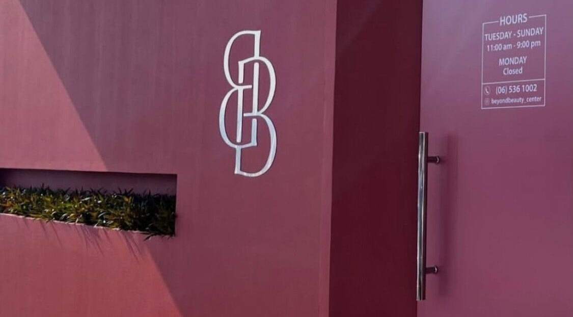 Entrance to Beyond Beauty, Ajman, AE, featuring sleek design and logo on a modern maroon facade.