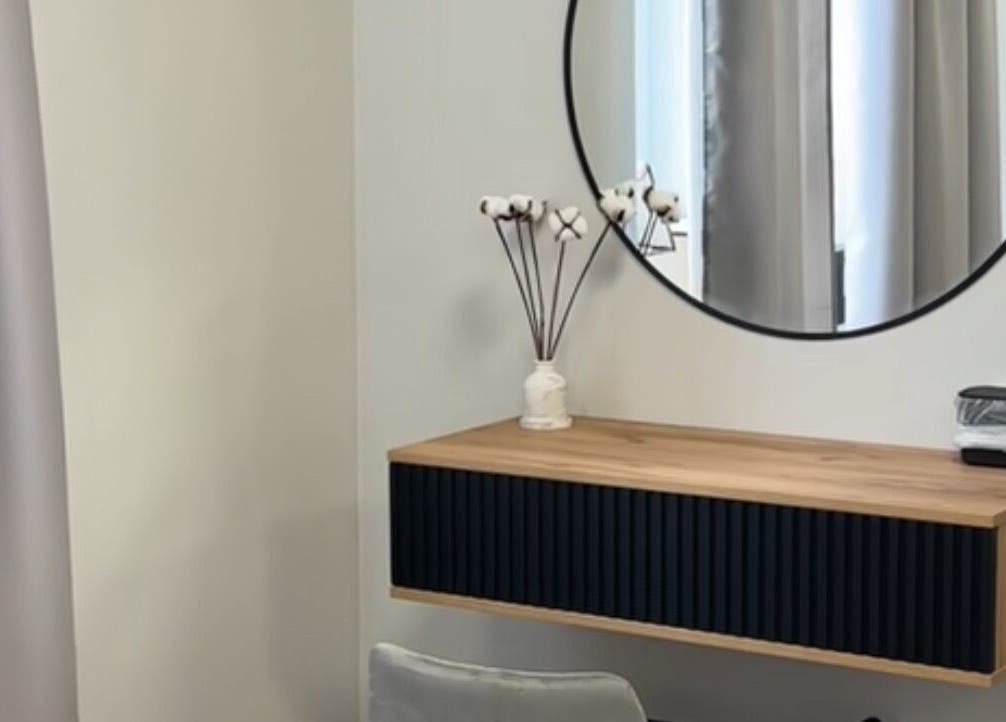 Modern vanity setup in Yaba with circular mirror and wooden shelf, located in Lagos, NG.