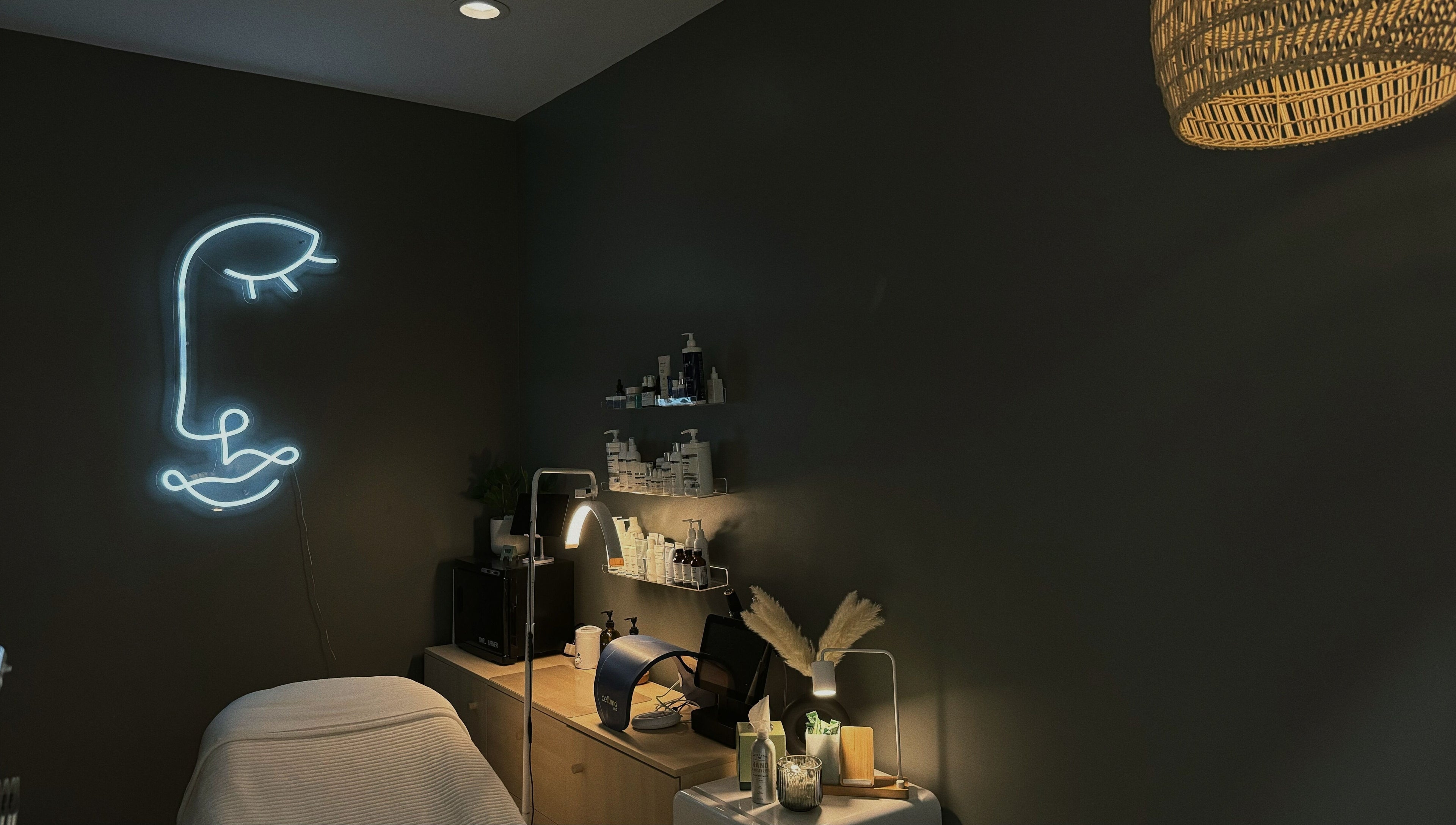 Lyla Skin Studio treatment room with neon face art in Aliso Viejo, California, US.
