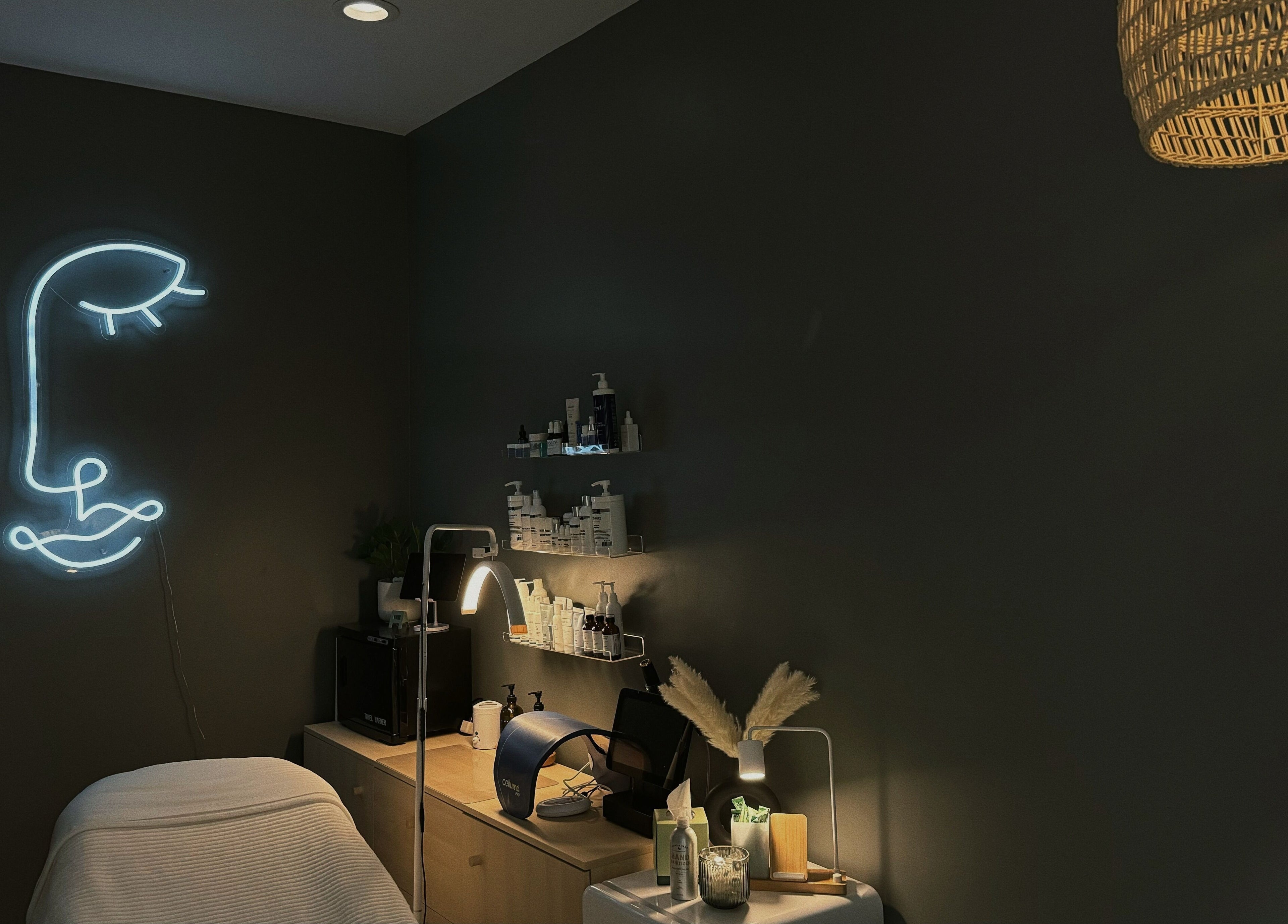 Lyla Skin Studio treatment room with neon face art in Aliso Viejo, California, US.