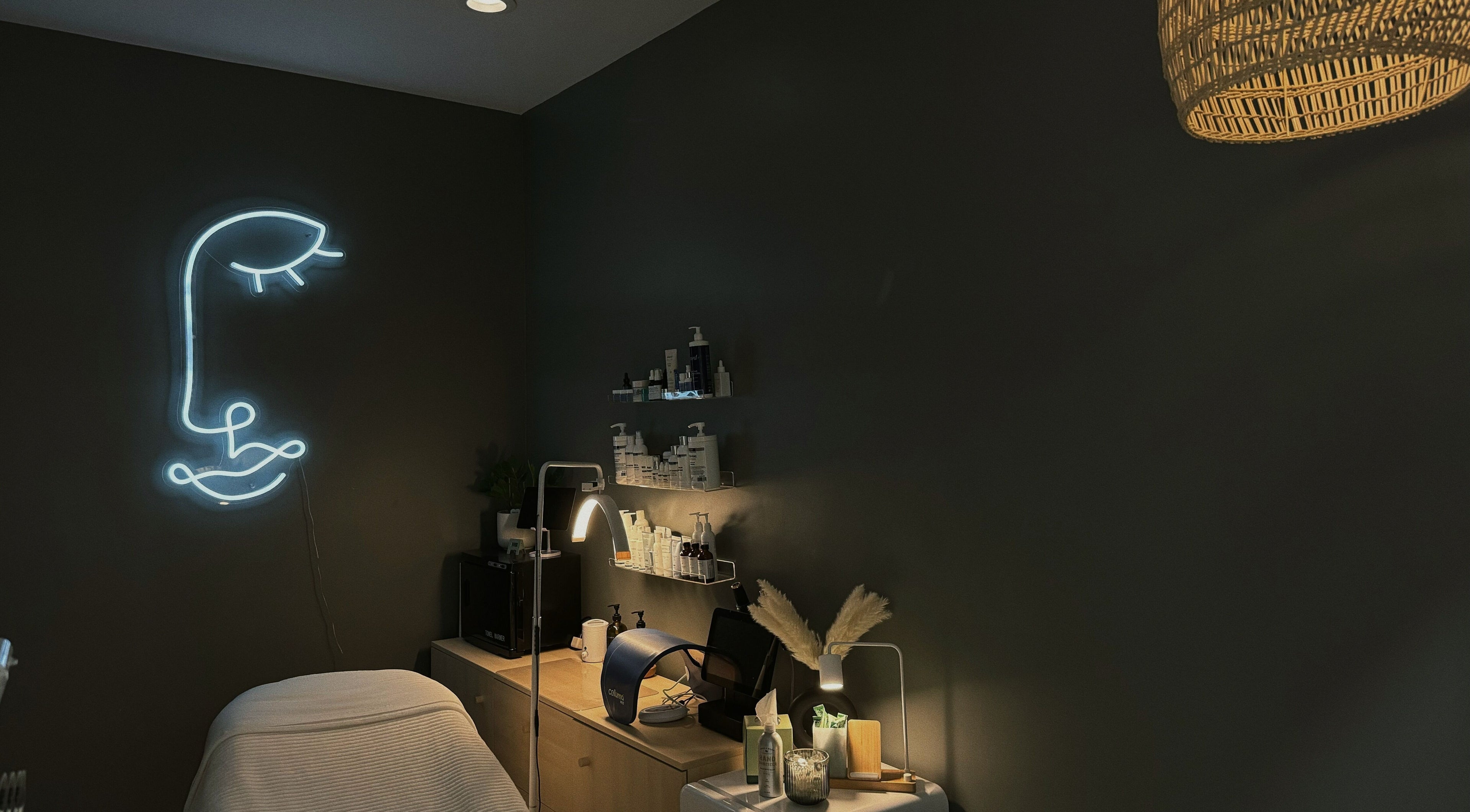 Lyla Skin Studio treatment room with neon face art in Aliso Viejo, California, US.