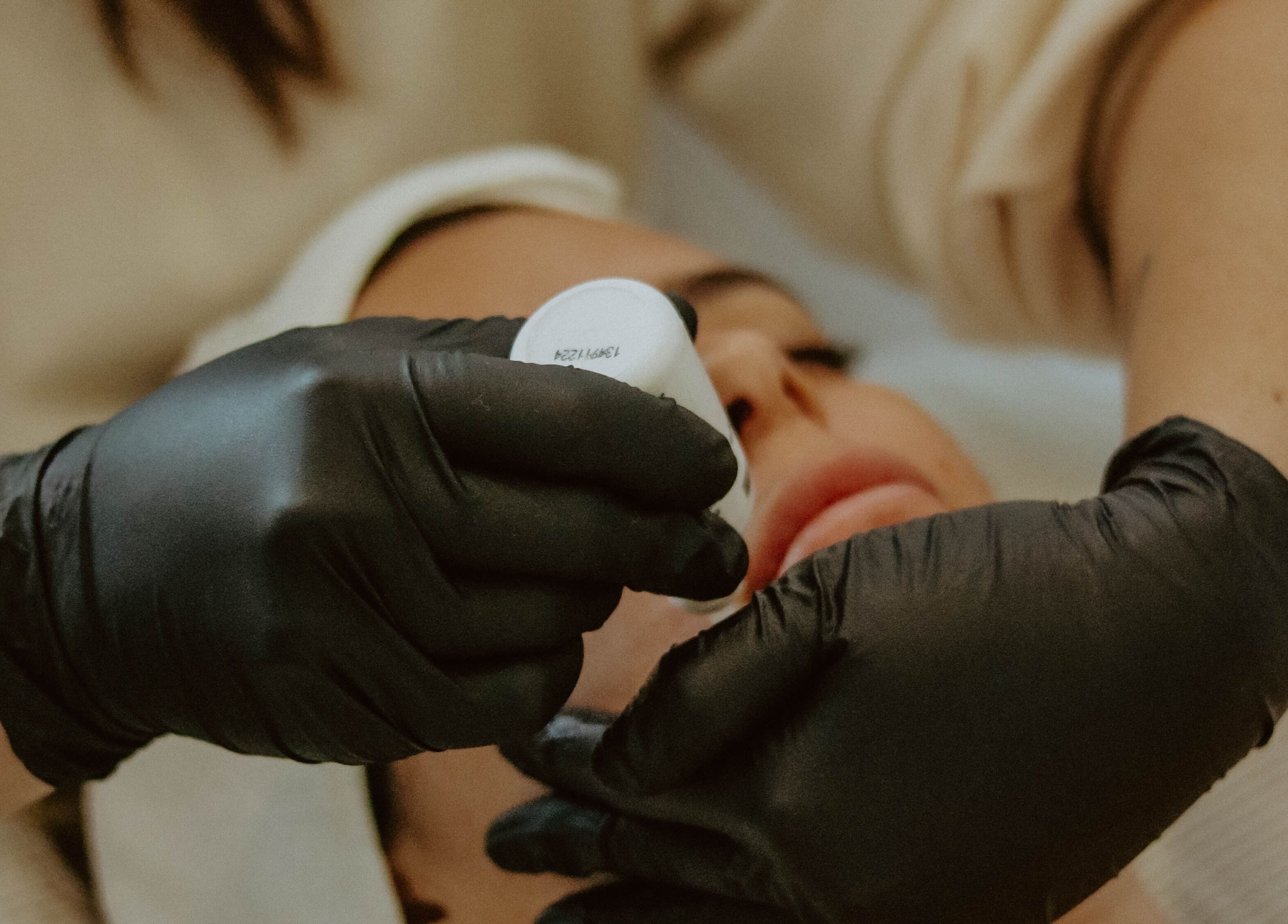 Facial treatment at Lyla Skin Studio in Aliso Viejo, California, US with gloved hands applying skincare.