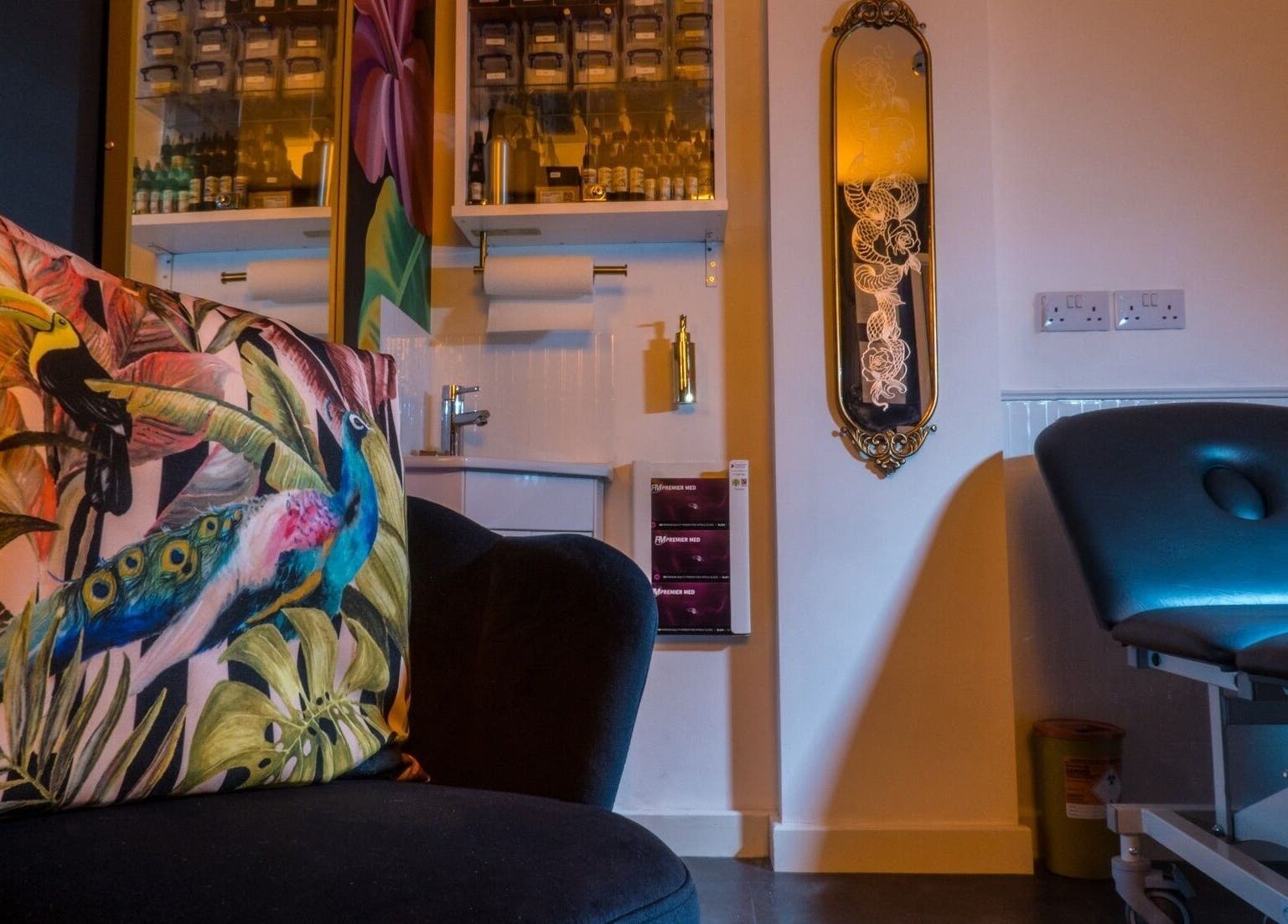 Relaxing corner at Lucky Bird Tattoo Studio, Somerton, England, GB featuring a vibrant tropical pillow and sleek tattoo chair.