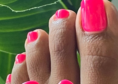 Bright pink pedicure at Palangana Spa, Willemstad, Curaçao, CW with lush green background.