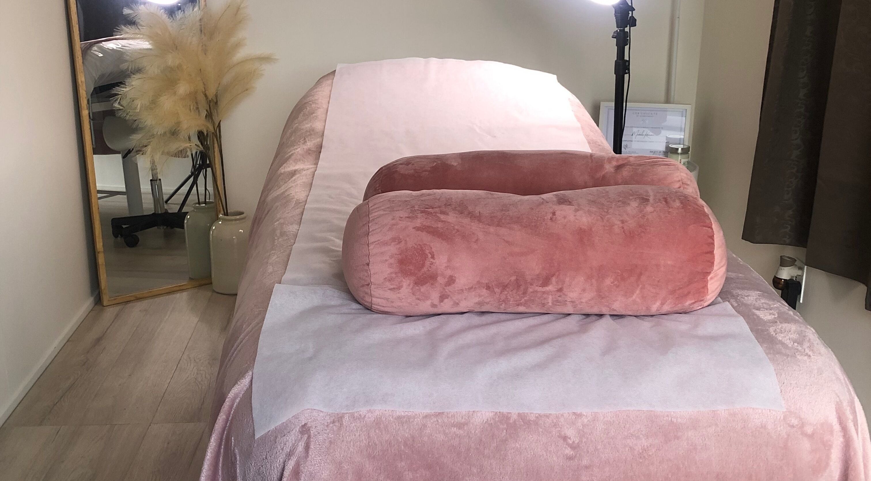 Peaceful treatment room at MK Brows & Beauty, Auckland, NZ, featuring pink plush bedding and elegant decor.