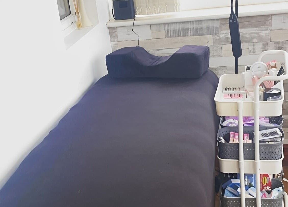 Treatment room in Lashes by Hayley, Morecambe, England, GB with a cozy bed and organized beauty cart.
