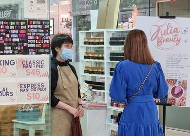A client chooses nail services at Julia Beauty at Orchard, Singapore, SG with a wide array of colorful nail designs.