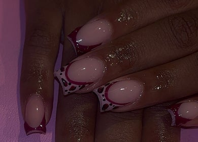 Stylish nail art at That Girl Collection in Ajax, CA showcasing intricate red and black patterns.