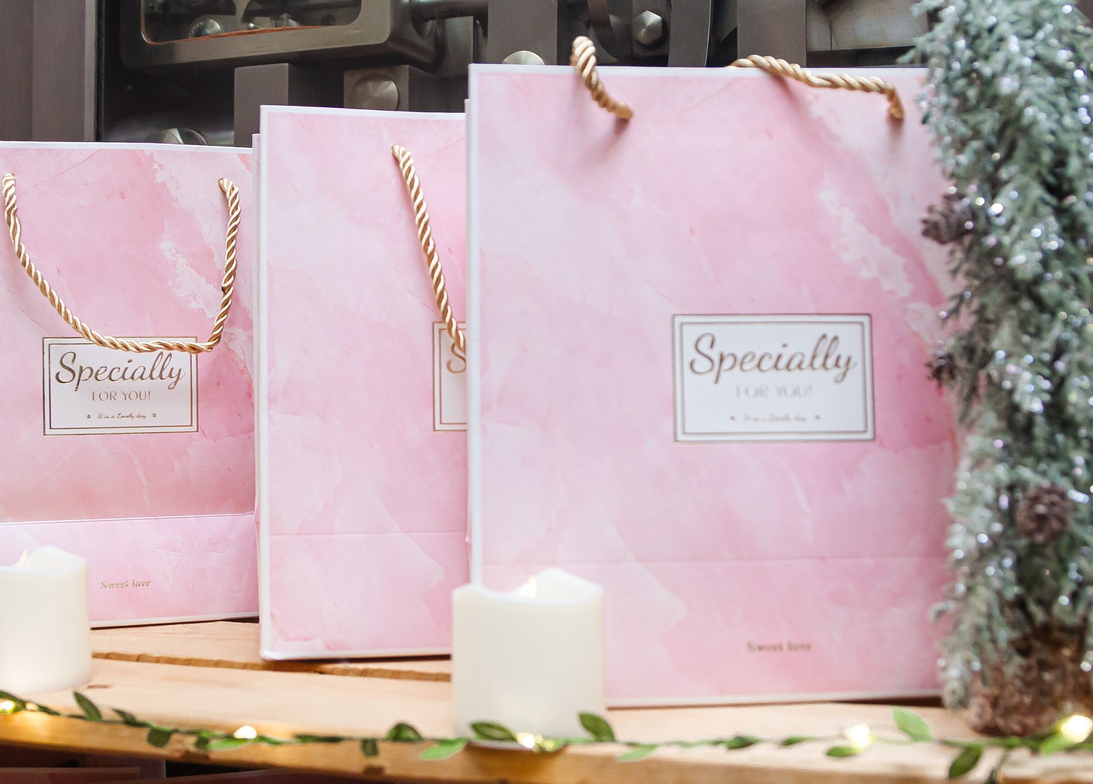 Pink gift bags at Zen Beauty Lounge, Stroudsburg, Pennsylvania, US, on a wooden surface with candles.