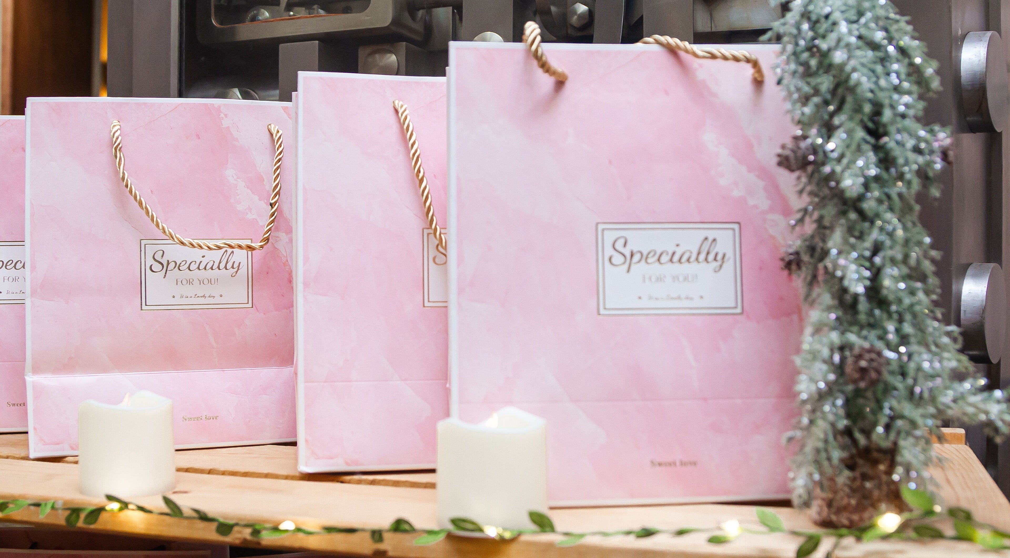 Pink gift bags at Zen Beauty Lounge, Stroudsburg, Pennsylvania, US, on a wooden surface with candles.