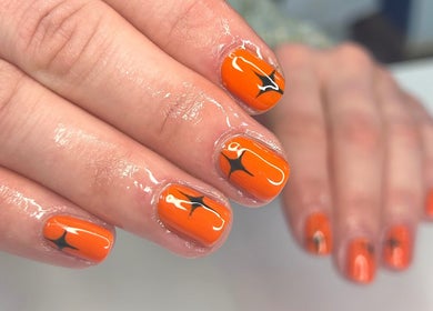 Bright orange nail art at Jade Saunders Nails in Rugby, England, GB showcasing intricate black detailing.