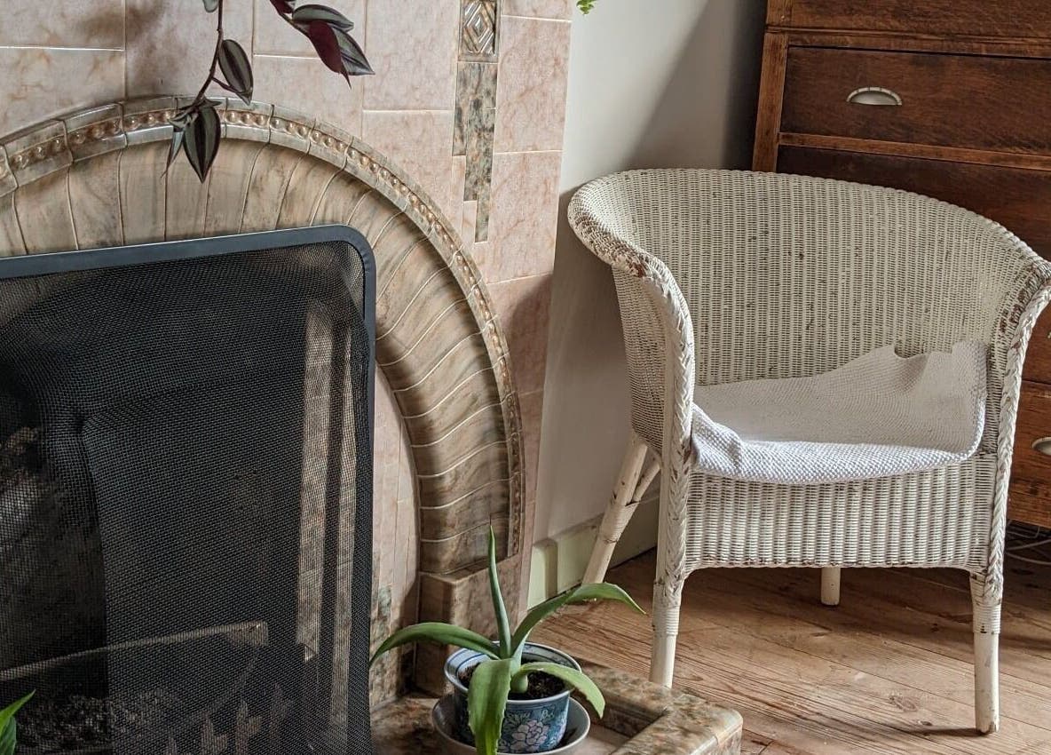 Relaxing chair by fireplace at The Cedar Room, Cullompton, England, GB offers warmth and comfort.