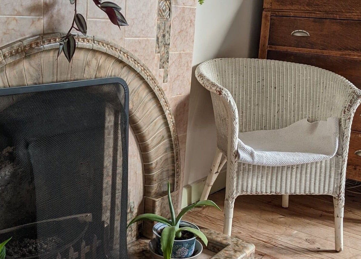 Relaxing chair by fireplace at The Cedar Room, Cullompton, England, GB offers warmth and comfort.