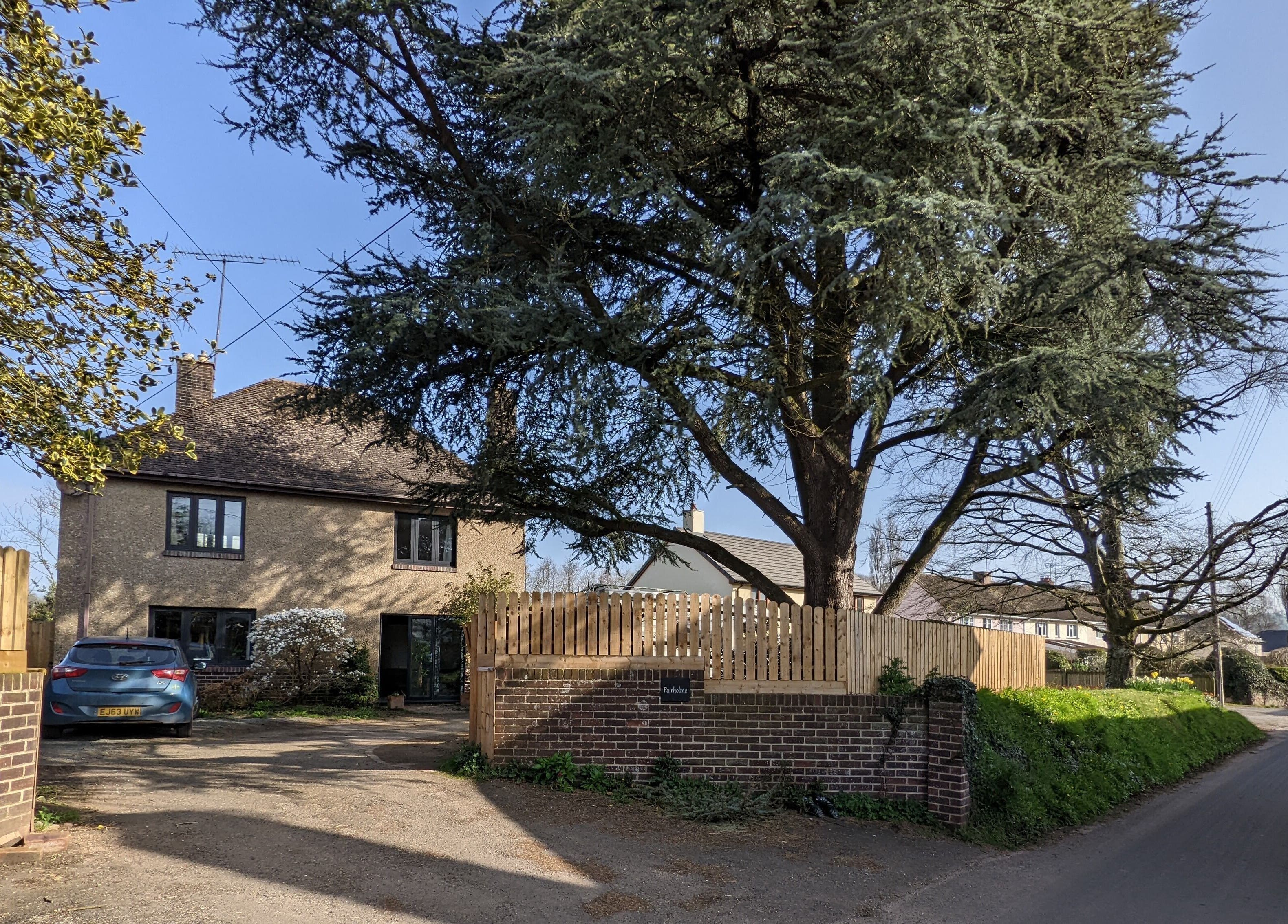 Charming exterior of The Cedar Room in Cullompton, England, GB with lush greenery and blue skies.