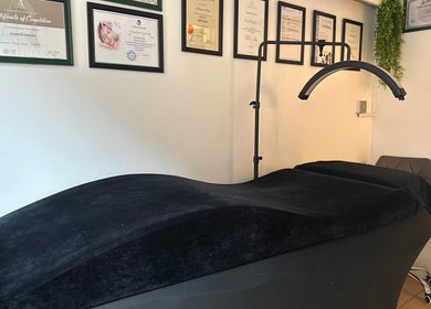 Treatment room at Selfie Lounge, London, England, GB, featuring massage bed and certification wall decor.