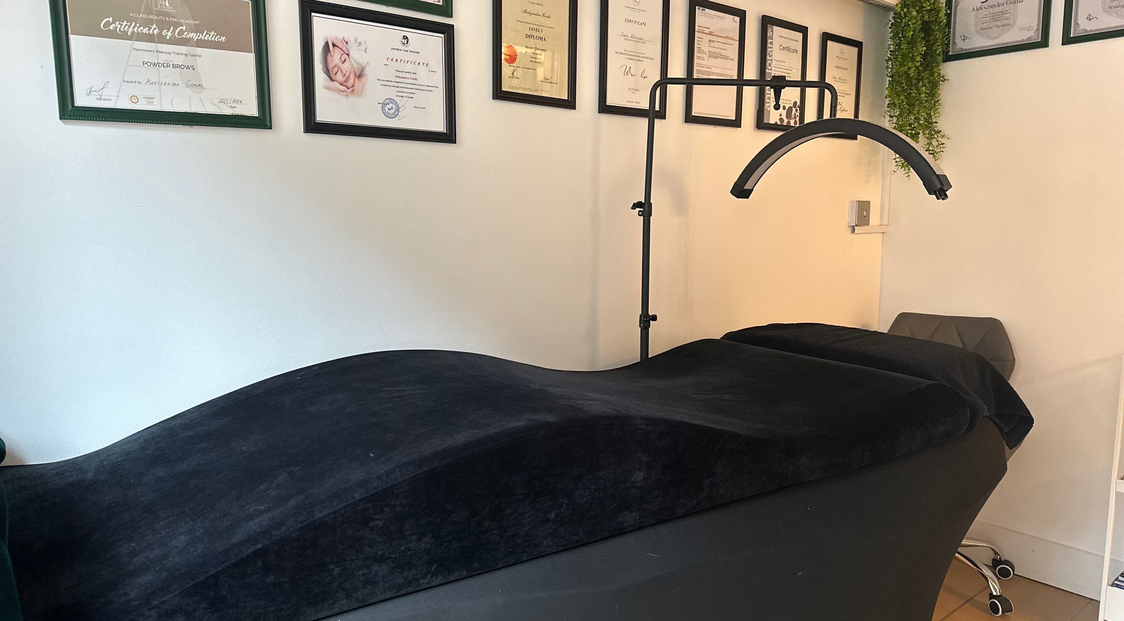 Treatment room at Selfie Lounge, London, England, GB, featuring massage bed and certification wall decor.
