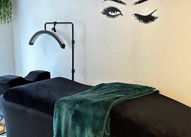 Relaxing treatment room at Selfie Lounge, London, England, GB with a sleek black couch and vibrant green blanket.