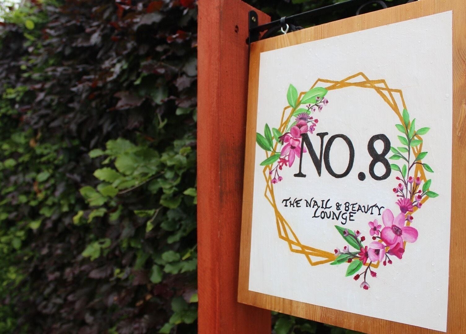 Sign of No.8 The Nail and Beauty Lounge in Gressenhall, England, adorned with vibrant floral design.