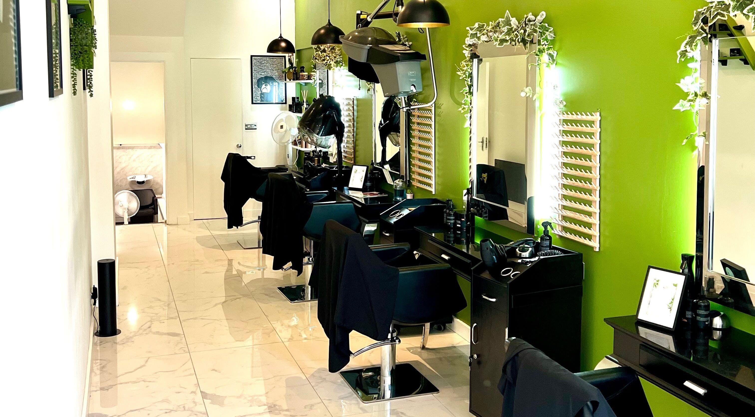 Stylish salon chairs and mirrors at The Braiding Vault Uk, London, England, GB with green accent wall.
