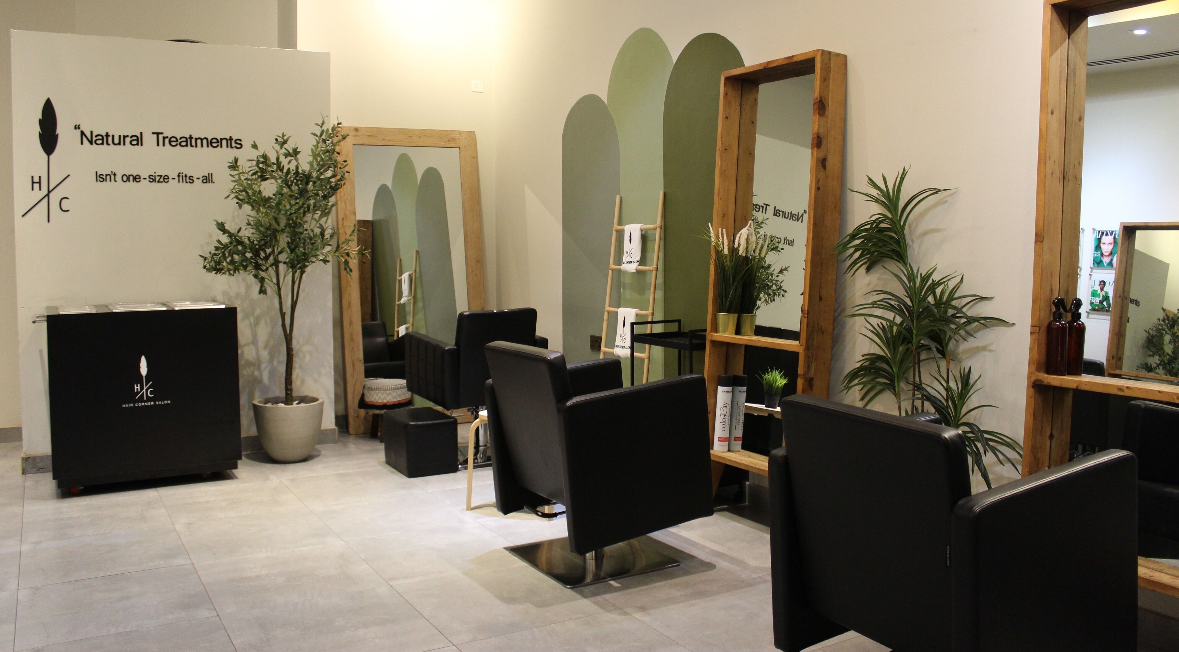 Modern interior of Hair Corner Salon in Dubai, Dubai, AE with sleek black chairs and lush greenery.