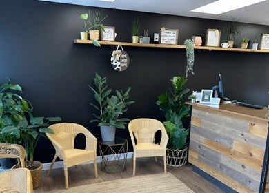 Reception area at Xoéy Nail Artistry, St. Albert, Alberta, CA, featuring greenery and wicker seating.