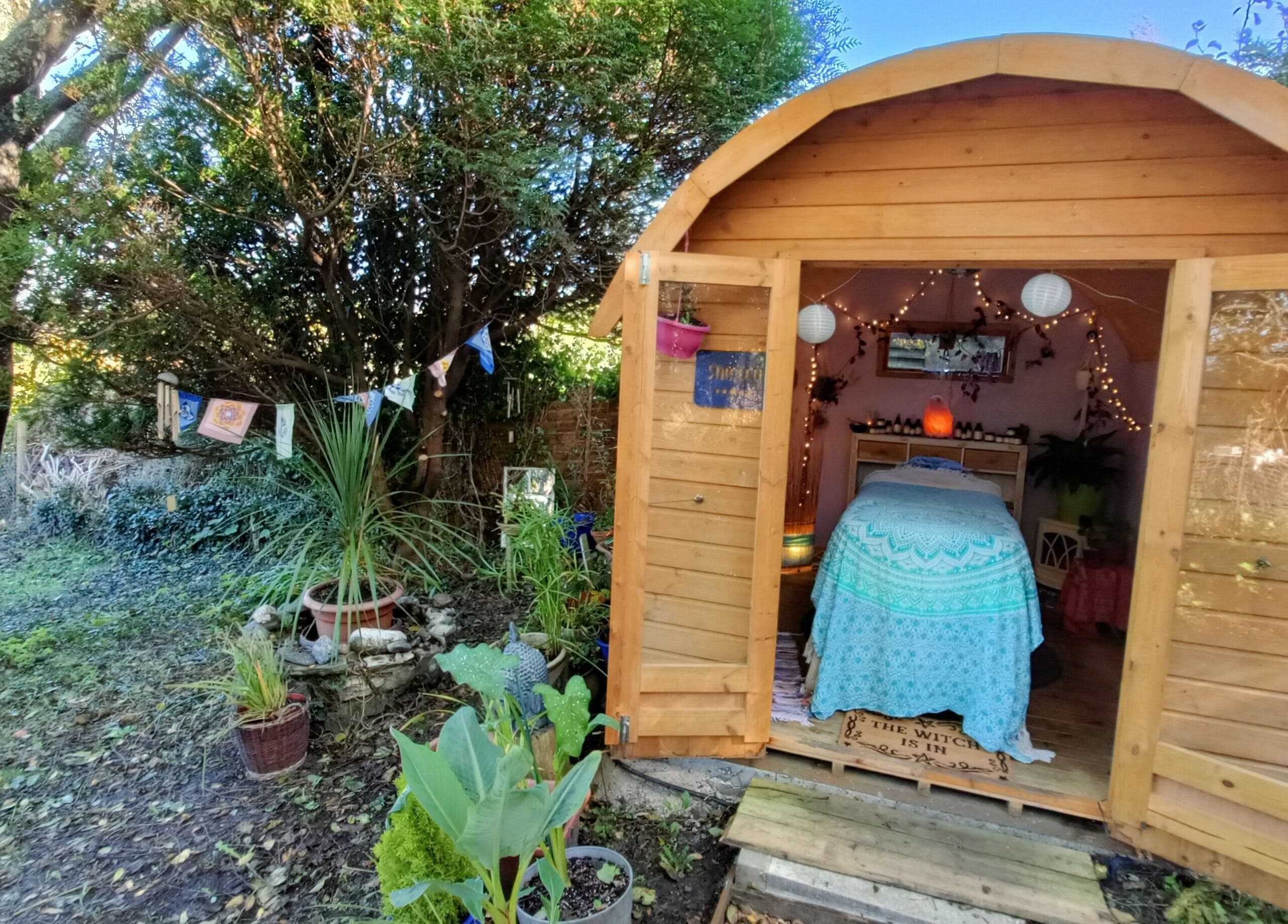 Rustic therapy cabin at Hayle Cornish Holistic Therapies in Hayle, GB, surrounded by lush greenery.