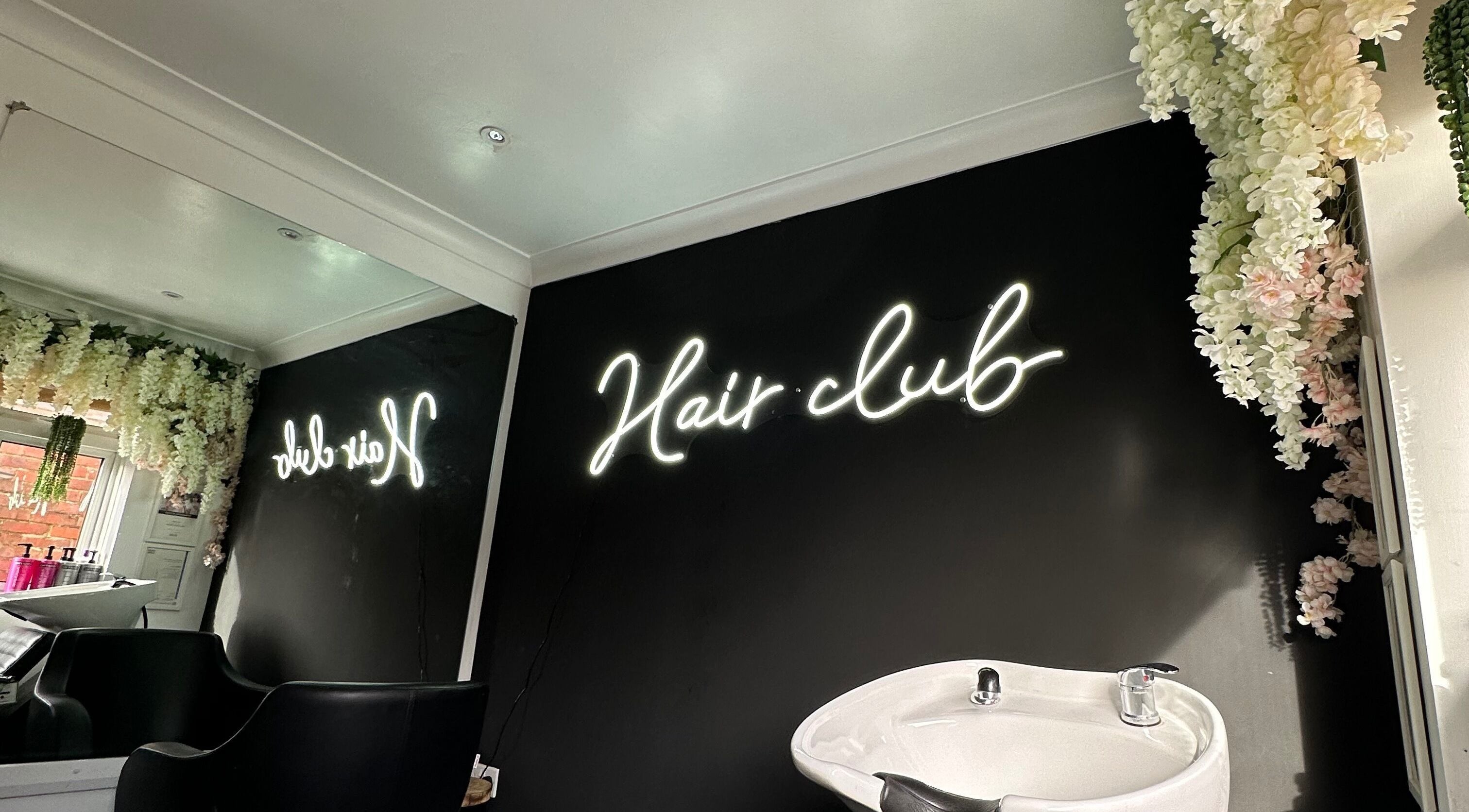 Stylish interior of The Hair Club, Waterlooville, England, GB with neon sign and elegant decor.