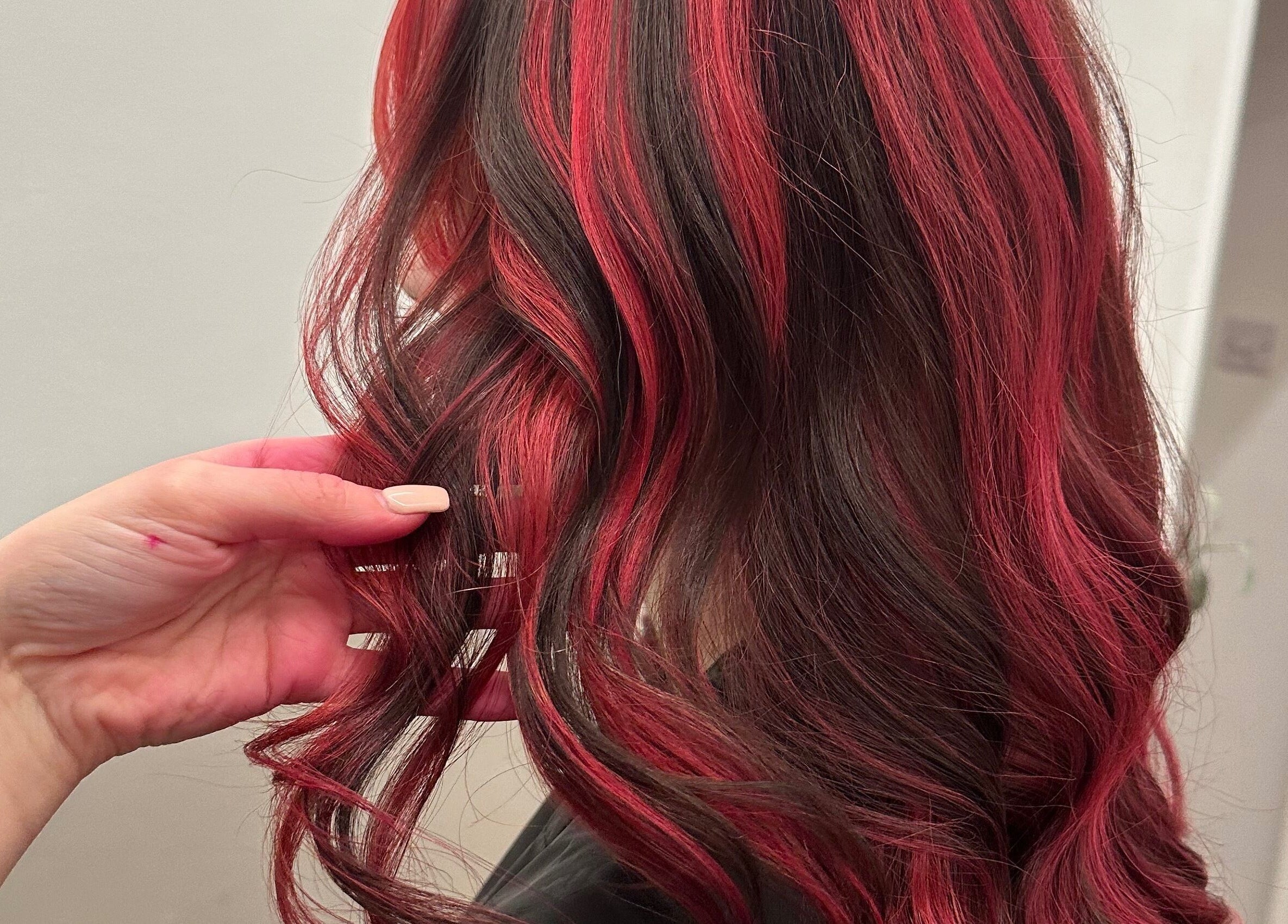Stylish red balayage at The Hair Club, Waterlooville, England, GB enhancing flowing curls.