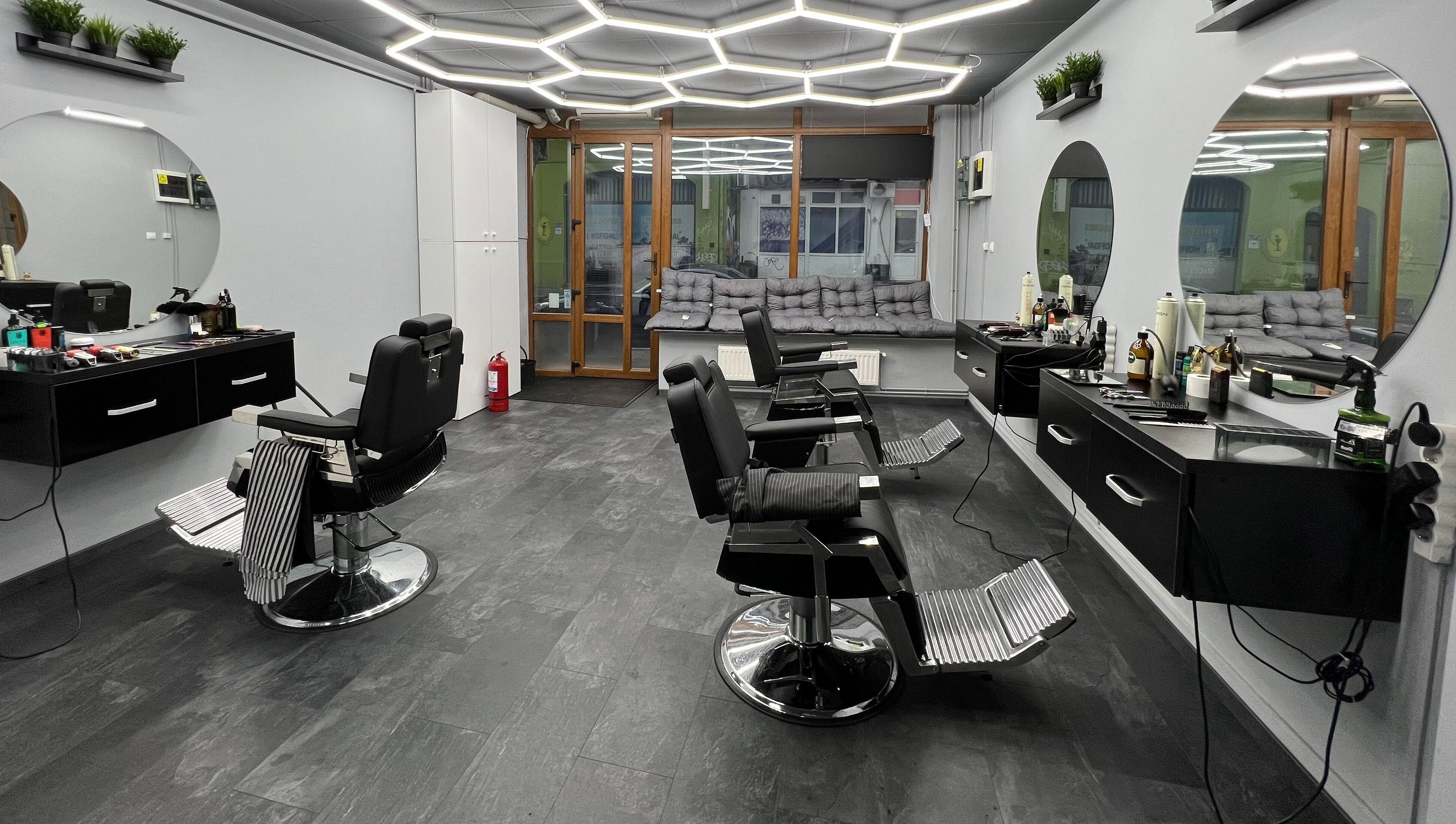 Interiorul modern al Damoti Barbershop din București, București, RO, cu scaune și oglinzi elegante.