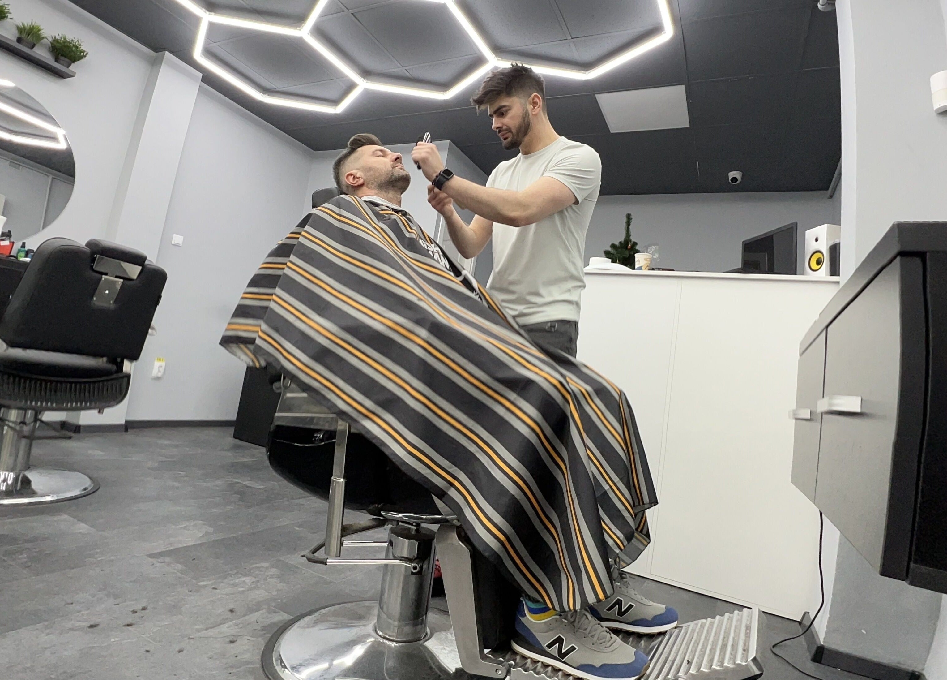 Interiorul Damoti Barbershop București, București, RO, cu un frizer oferind un serviciu profesionist.