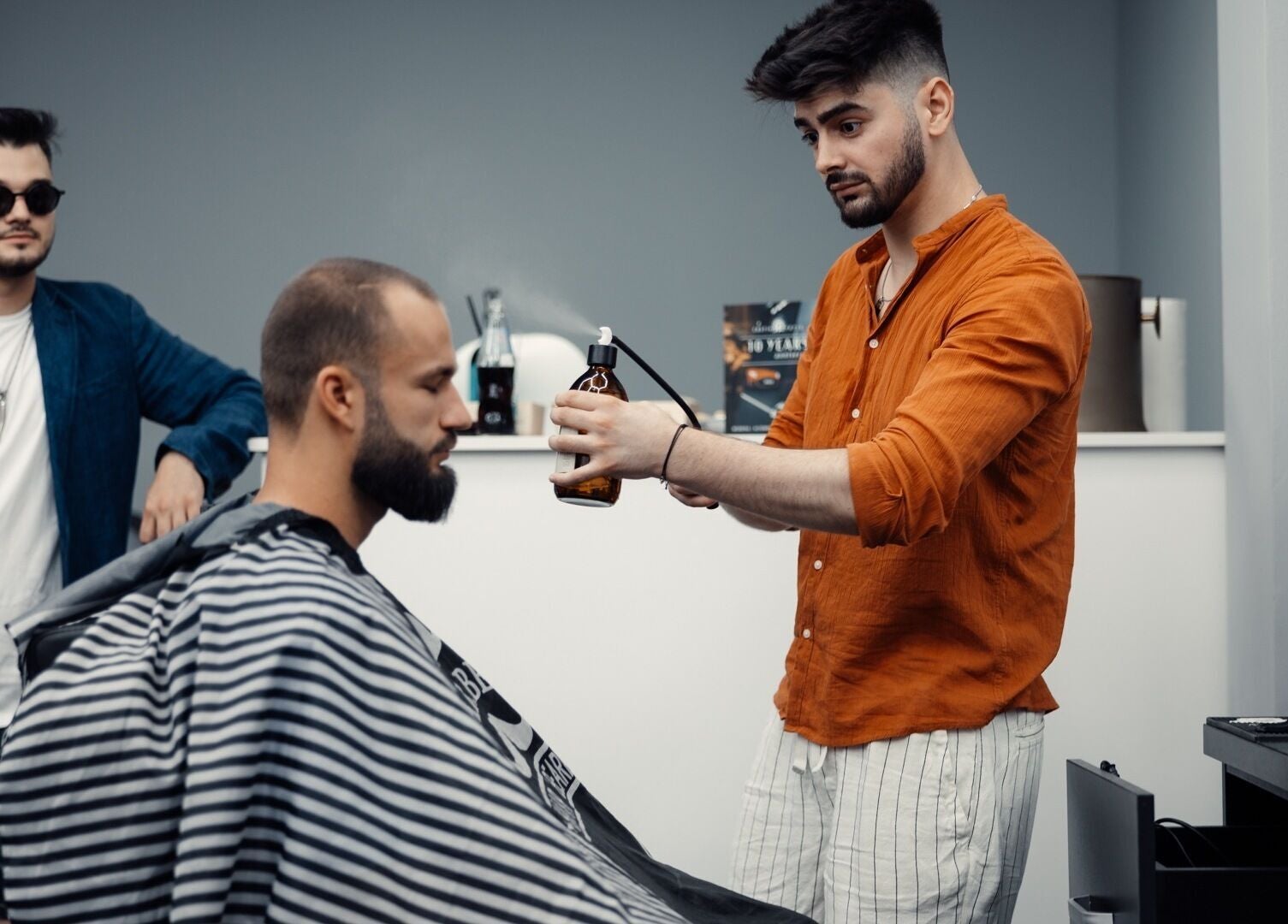 Frizer aplicând un spray clientului la Damoti Barbershop, București, București, RO.
