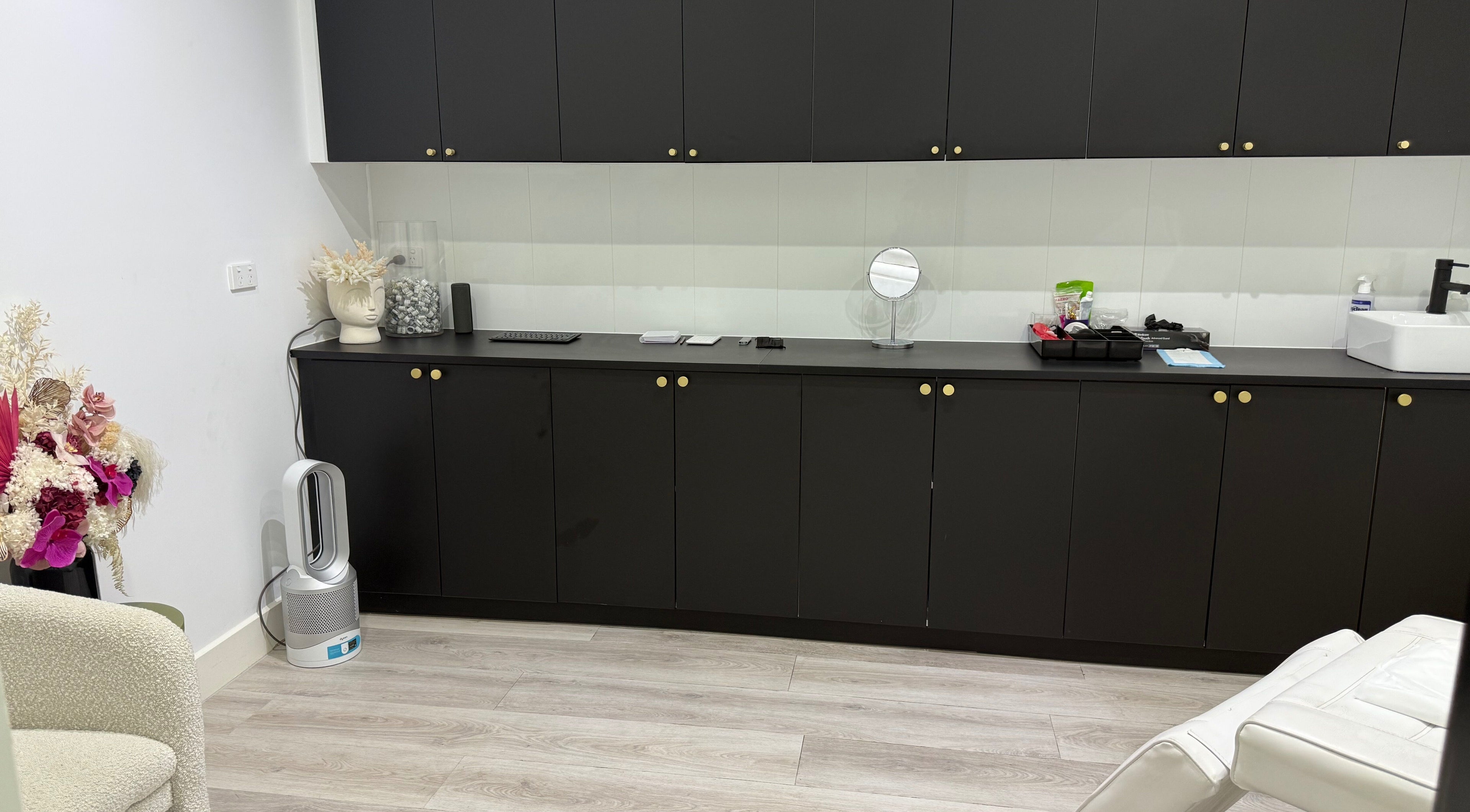 Modern treatment room at Cosmetic Effects, Ivanhoe, Victoria, AU, featuring sleek black cabinetry and decor.
