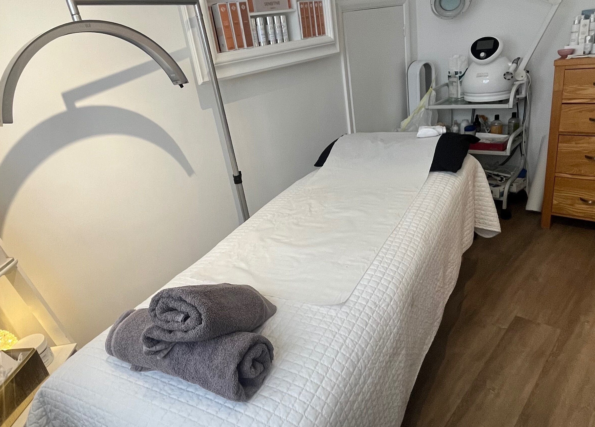 Tranquil treatment room at The Peel Queen, Addlestone, England, GB, featuring a treatment bed with neatly folded towels.